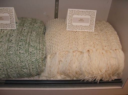 2 knitted afghans, both the same pattern, the green uses 2 yarns and doesn't have fringe
